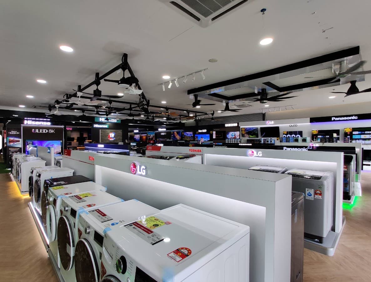 Tanradio 柔佛展厅 — 前景排列着洗衣机、天花板挂着展示风扇、后方延伸的 Hisense、Samsung、LG、Toshiba 和 Panasonic 品牌墙。