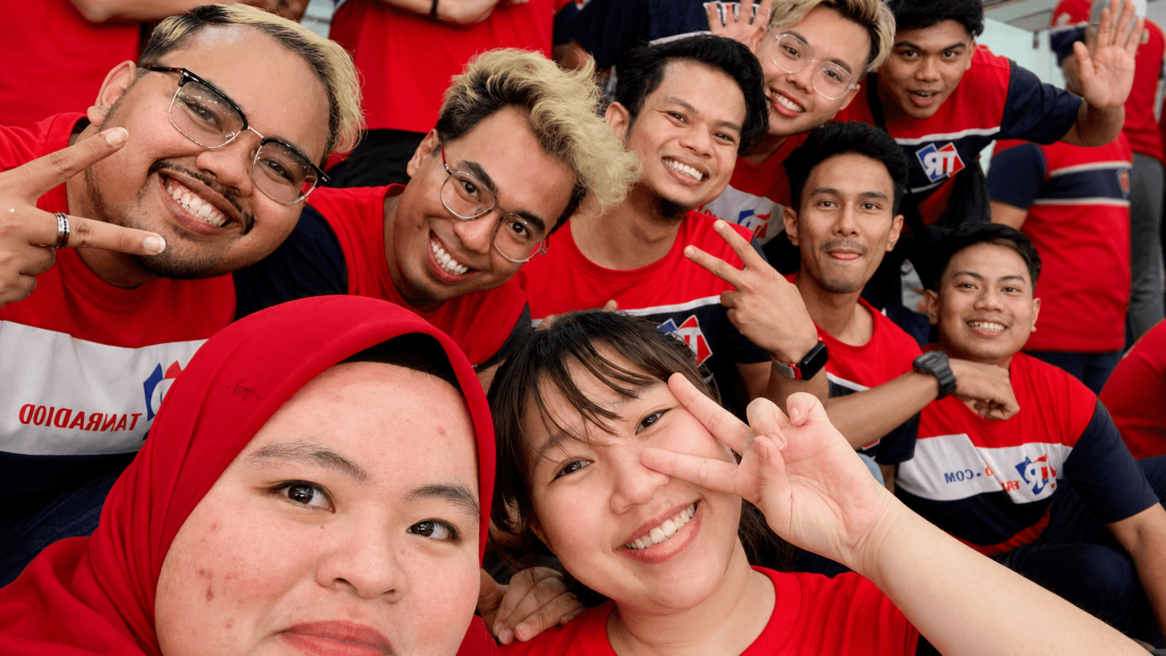 The Tanradio team — over a hundred and fifty people in red TR uniforms, smiling together at a company gathering.